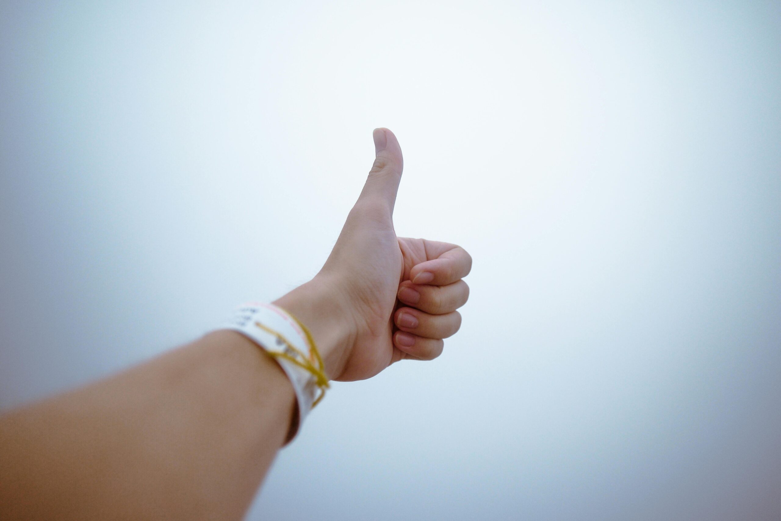 A hand giving a thumbs up gesture symbolizes approval and positivity