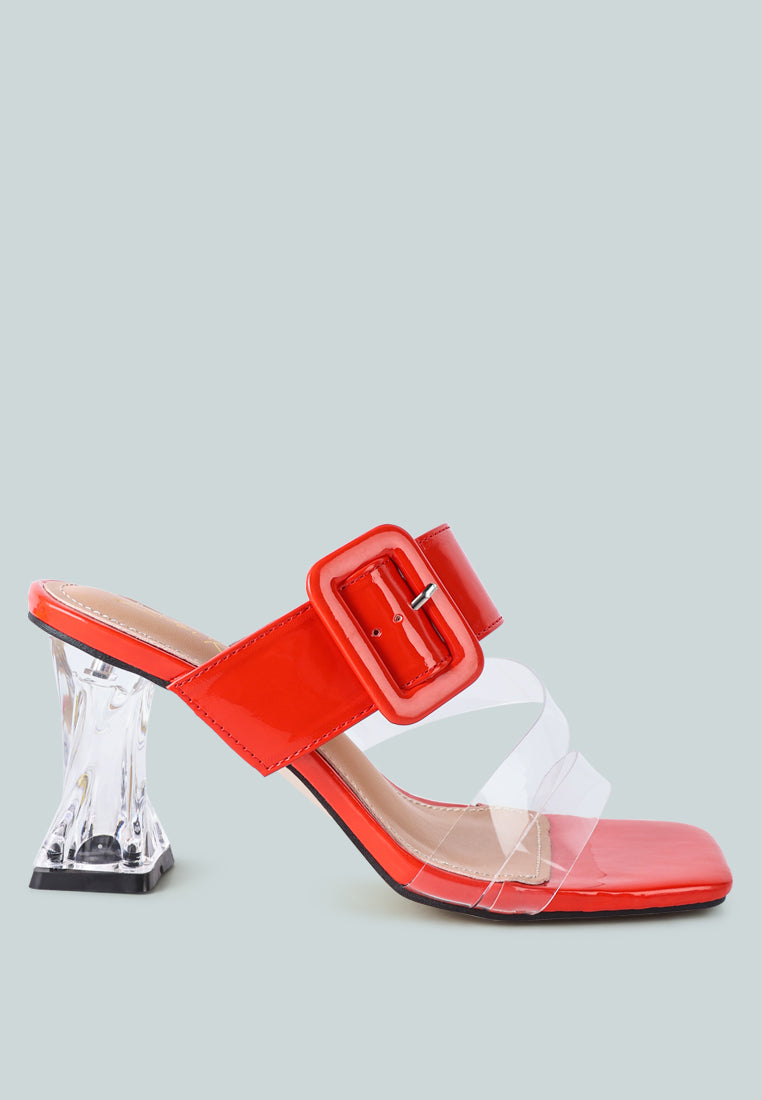 Red slide sandals with a clear strap and mid heel design. Red mid heel slide sandals featuring a clear strap and a decorative buckle.
