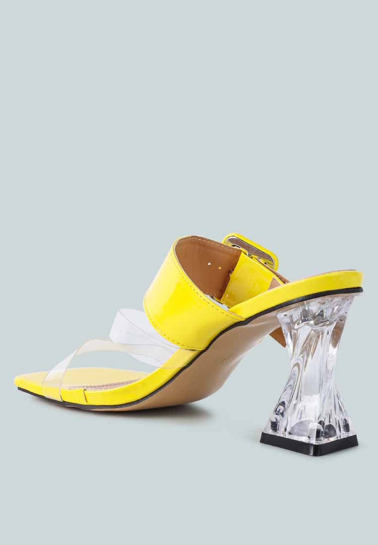 Yellow slide sandals with transparent straps and a distinctive heel. Yellow mid-heel slide sandals featuring transparent straps and a unique heel design.