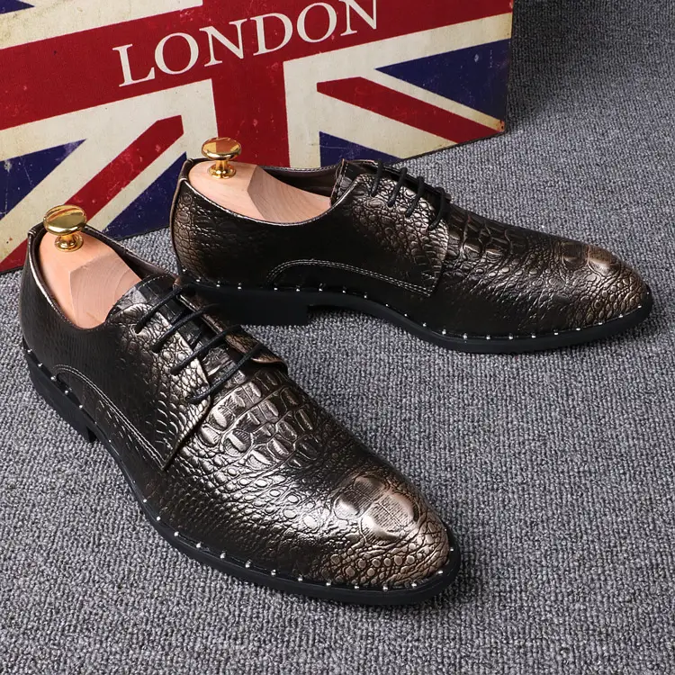 Brown crocodile pattern dress shoes with black soles. Brown dress shoes with a crocodile pattern and black soles placed on a gray surface.