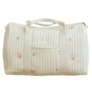 Quilted white duffle bag featuring bunny embroidery and a front pocket.