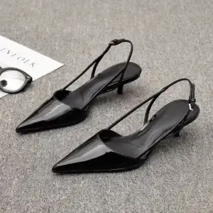 Pair of black patent leather slingback heels with pointed toes and a low heel.
