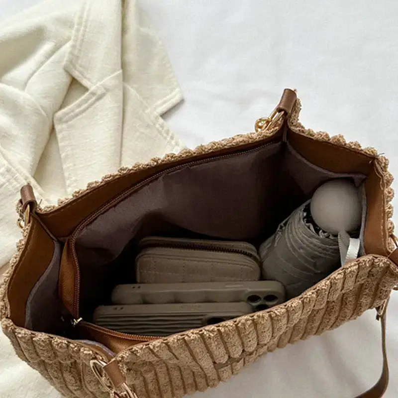 An open beige handbag displaying its interior contents. Open beige handbag showing various items inside including a wallet and a phone.