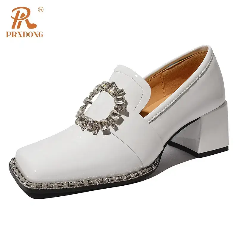 White heeled loafers with a decorative buckle detail. White heeled loafers featuring a decorative buckle and a square toe design.
