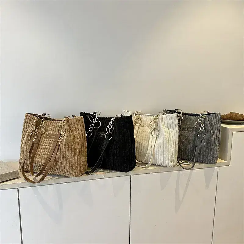 A collection of ribbed handbags in multiple colors. Five ribbed handbags in tan, black, white, gray, and dark gray displayed in a row.