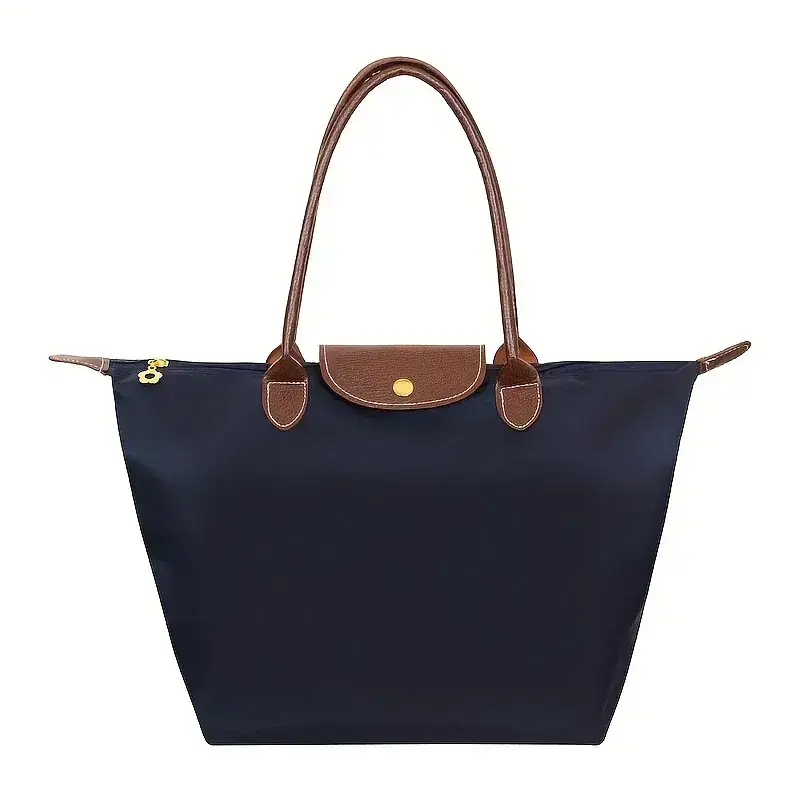 A navy blue tote bag with brown leather accents. Navy blue tote bag featuring brown leather handles and a snap closure.