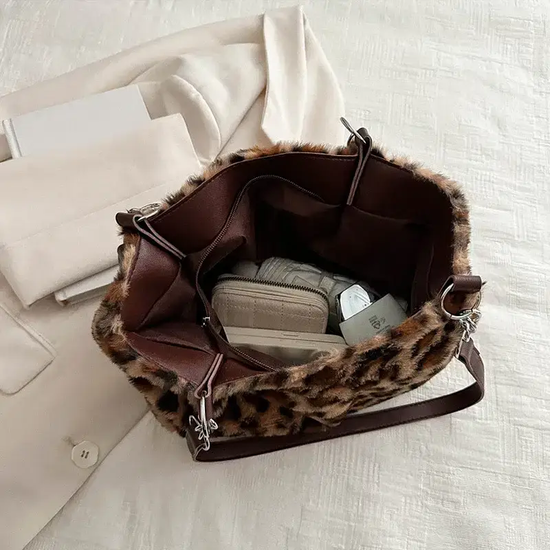 An opened leopard print tote bag displaying its contents. Leopard print tote bag opened to show contents including a wallet and other items.