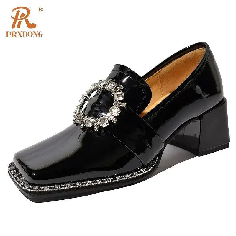Black patent leather loafers featuring a decorative buckle. Black patent leather loafers with a decorative rhinestone buckle on the upper and a block heel.