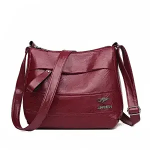 Red leather crossbody bag with a long adjustable strap and a zippered closure.