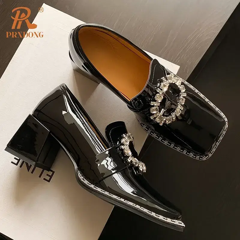 Black patent leather shoes with a decorative buckle detail. Black patent leather heeled shoes featuring a decorative buckle on the front.