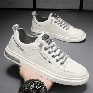 White casual sneakers with gray accents and laces, displayed on a hand.