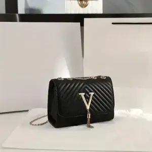 Black quilted handbag featuring a gold letter V and a chain strap on a white surface.
