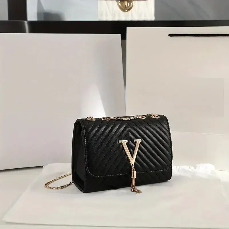 A black quilted handbag with a gold letter V and chain strap. Black quilted handbag featuring a gold letter V and a chain strap on a white surface.