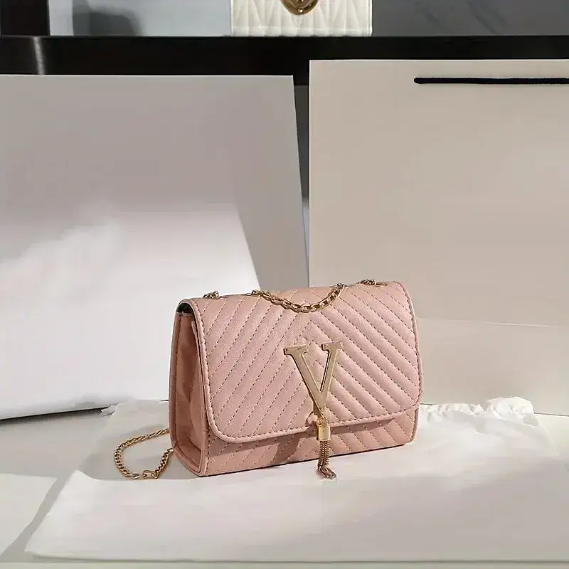 A pink quilted handbag featuring a chain strap and a prominent 'V' logo. Pink quilted handbag with a chain strap and a 'V' logo on the front.