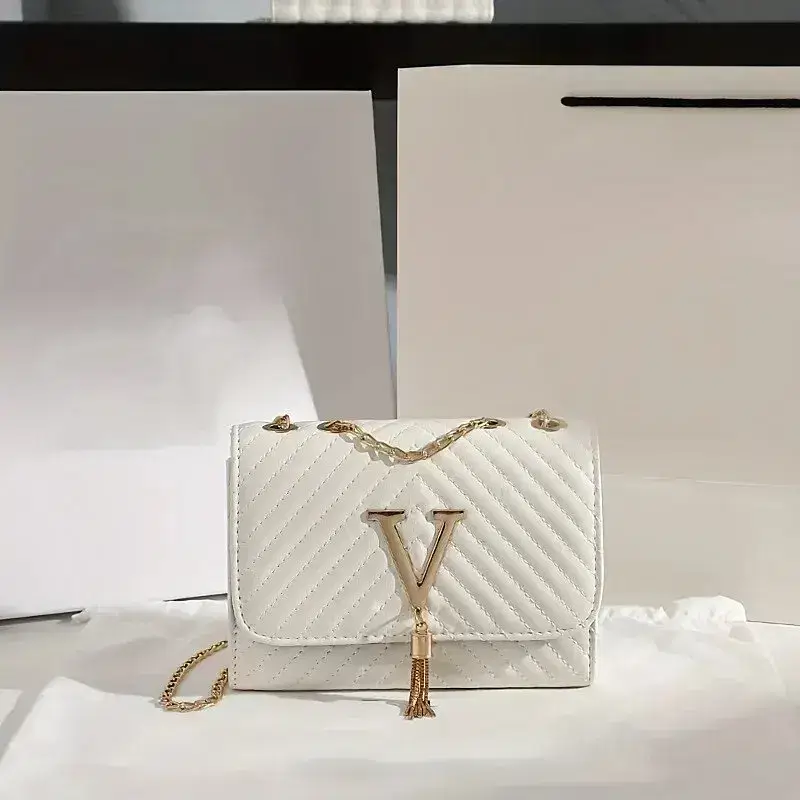 A white quilted handbag with a gold chain strap. White quilted handbag featuring a gold chain strap and a prominent 'V' logo on the front.
